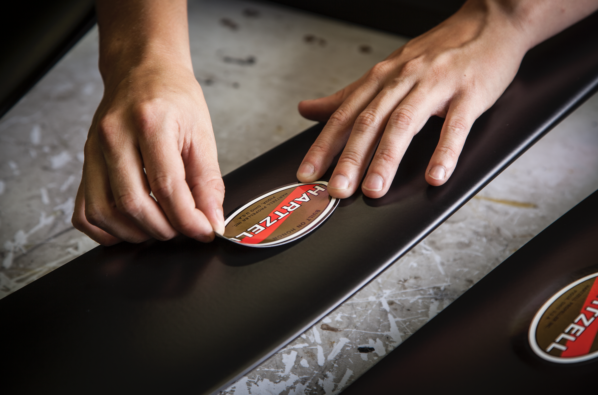 Hands placing Hartzell sticker on propeller blades