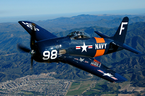 Blue and orange F8F Bearcat aircraft flying over Chino, California