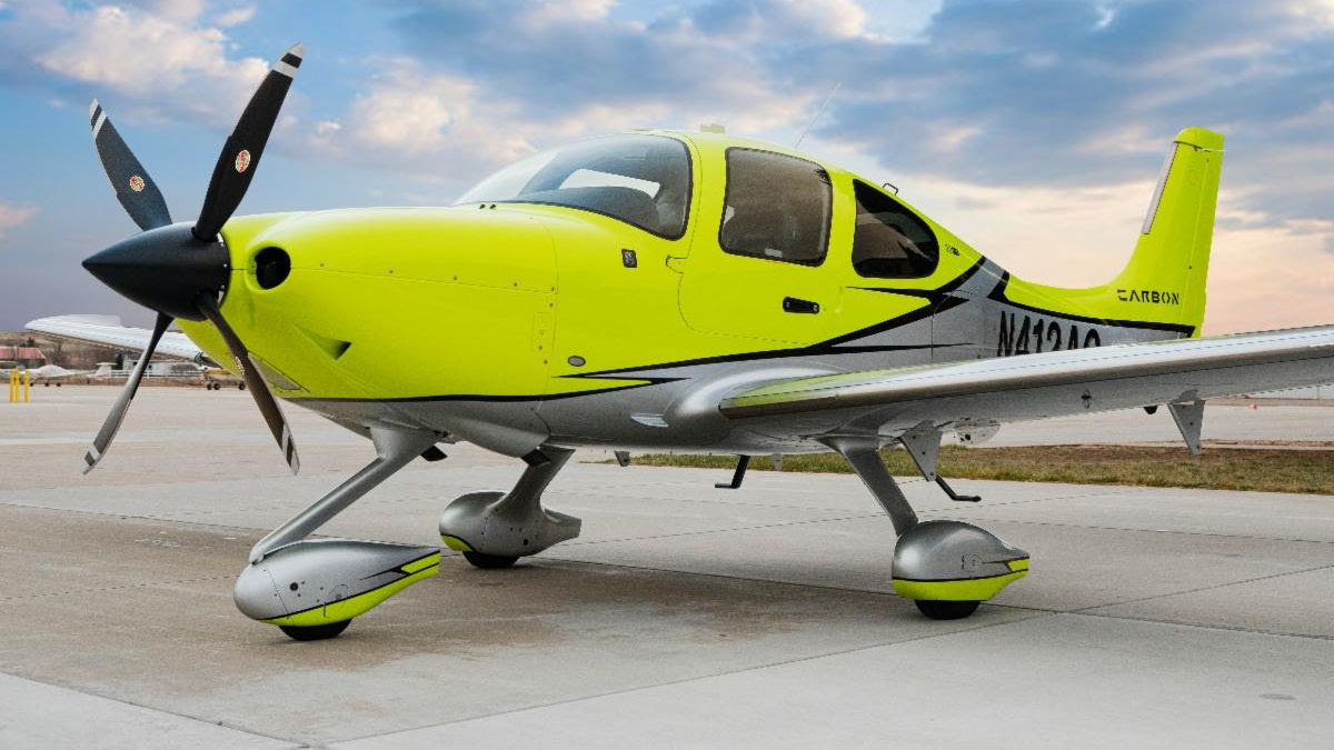 A neon green single-engine, low-wing Cirrus SR22 turbo in a three quarter head on view from below on the ramp.